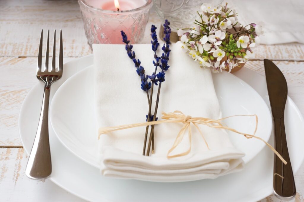 A plate with silverware decorated with flowers next to a lit candle.