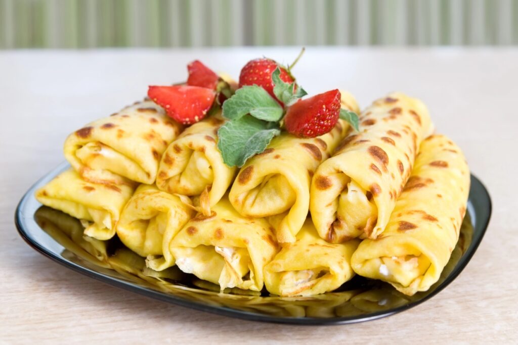 Cheese blintz on a plate with sliced strawberries.