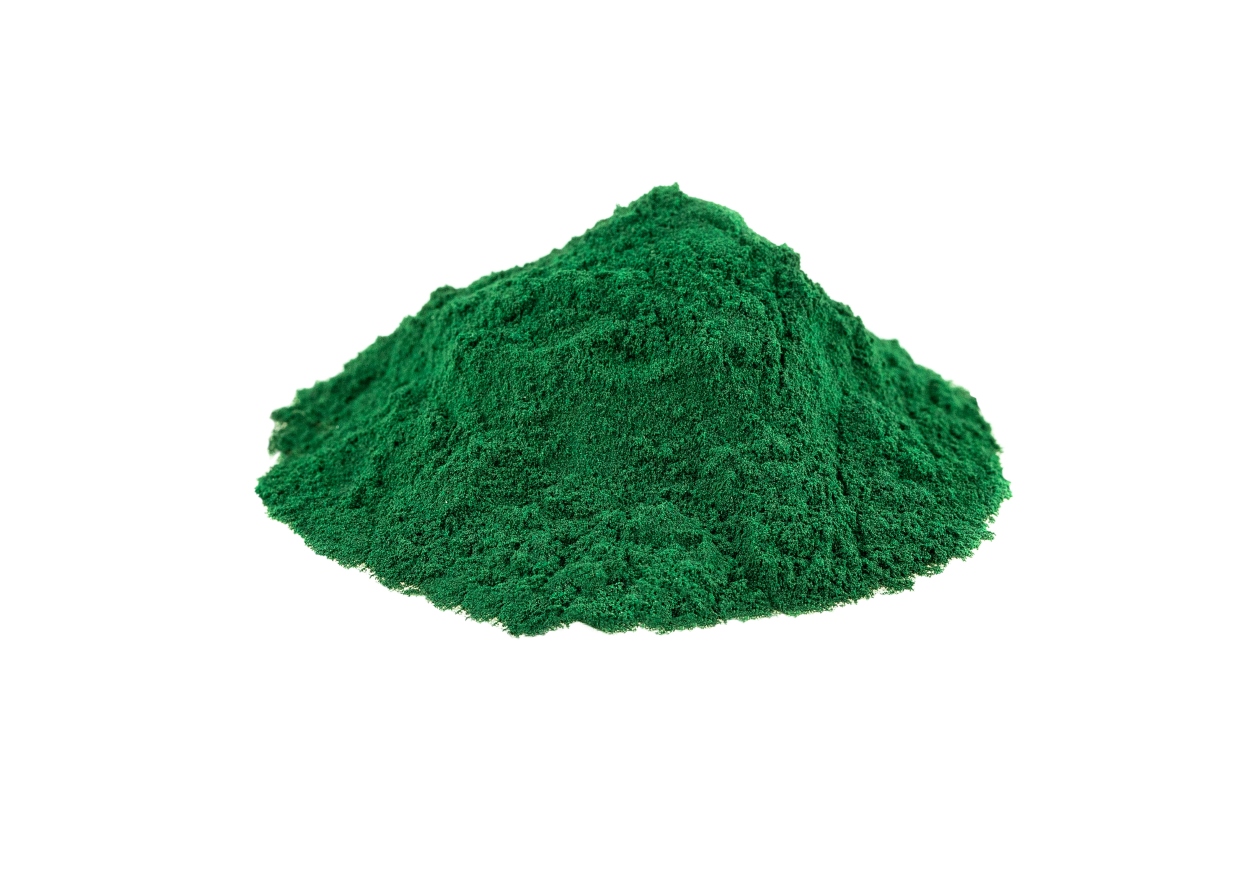 A small pile of vibrant green powder is centered on a plain white background.