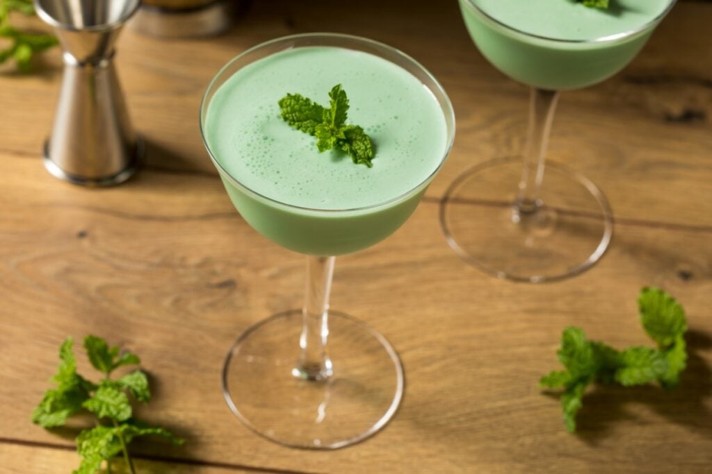 Grasshopper cocktail on a wood table garnished with fresh mint.