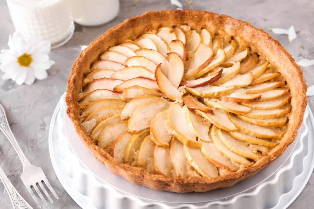 Apple pie with sliced apples on a serving tray.