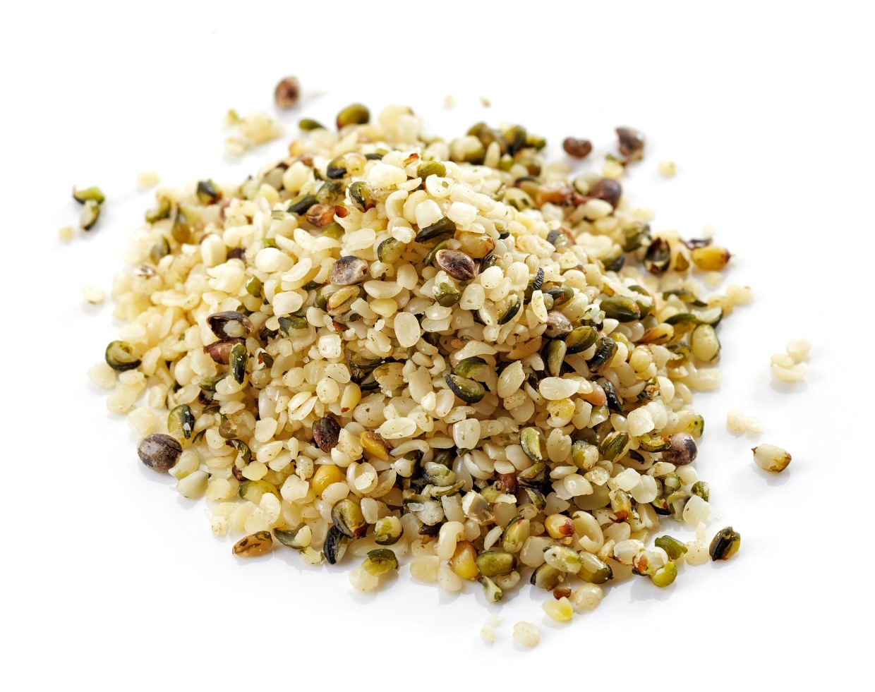 A pile of hemp seeds on a white background. The seeds are small, shelled, and vary in color from beige to green, with some darker spots.