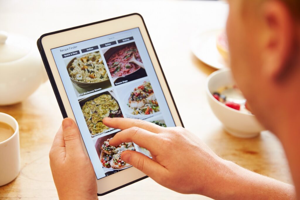 A person clicking on a tablet to plan holiday recipes.