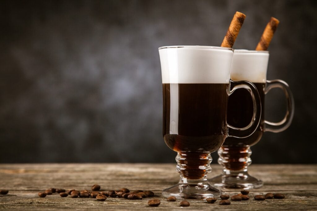 Irish Coffee cocktail next to some whole coffee beans.