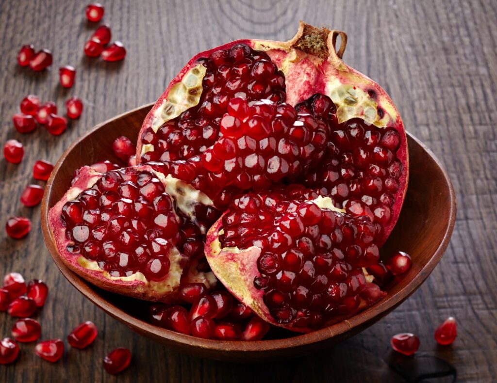 A pomegranate in a bowl with seeds.