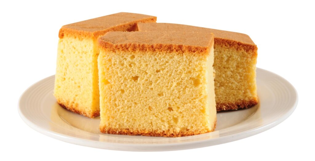 Three slices of fluffy sponge cake are arranged on a white plate. The cake has a golden brown crust on top and a light yellow, airy interior, showcasing a soft and delicate texture.