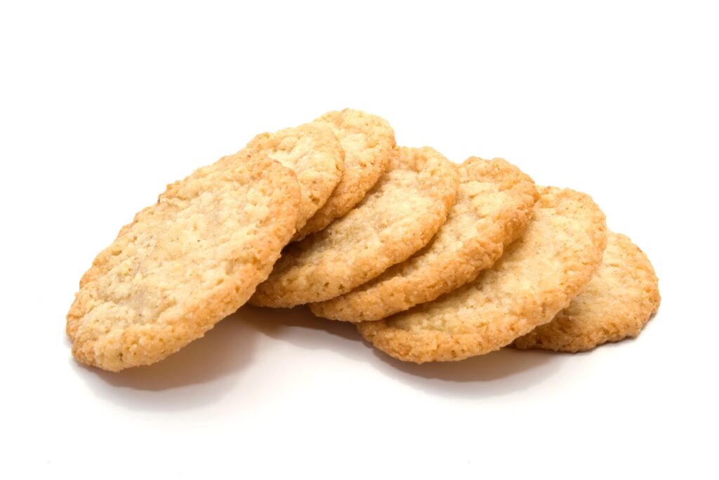 Five golden-brown cookies are arranged in a slightly overlapping row against a plain white background. They have a rough, crumbly texture and appear freshly baked.