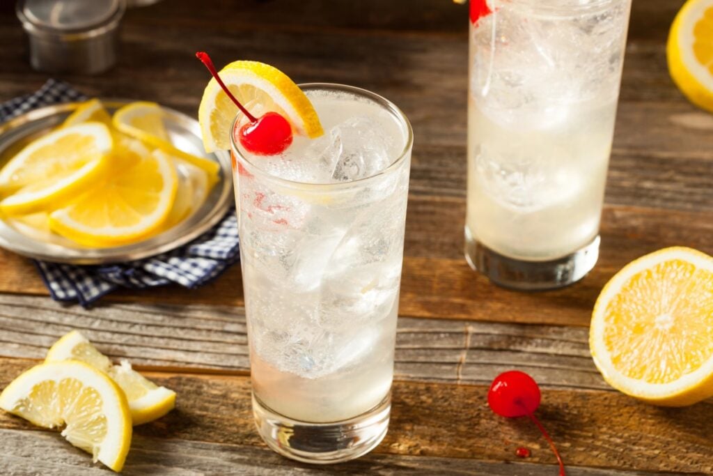 Tom Collins cocktail garnished with a cherry and a lemon slice.