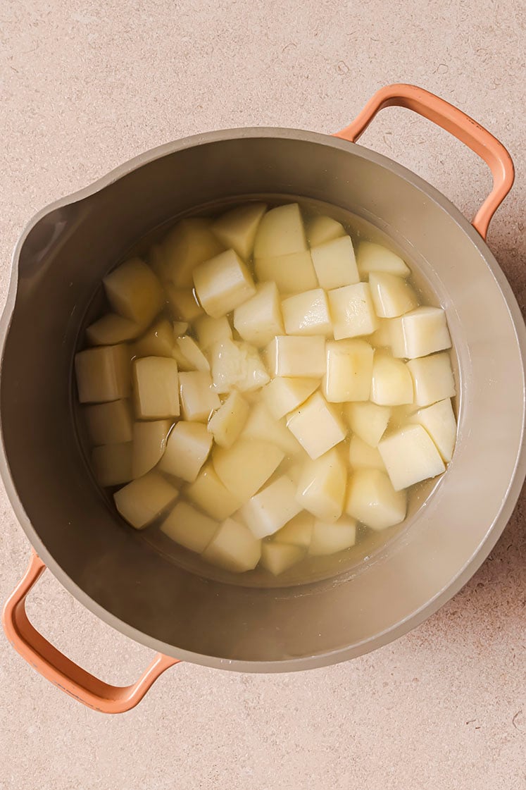 A pot filled with cubed potatoes soaking in water.