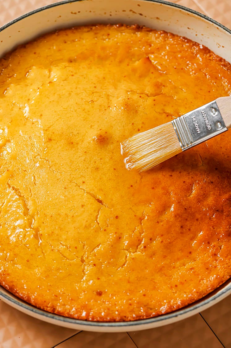 Honey butter skillet cornbread batter being brushed with honey.