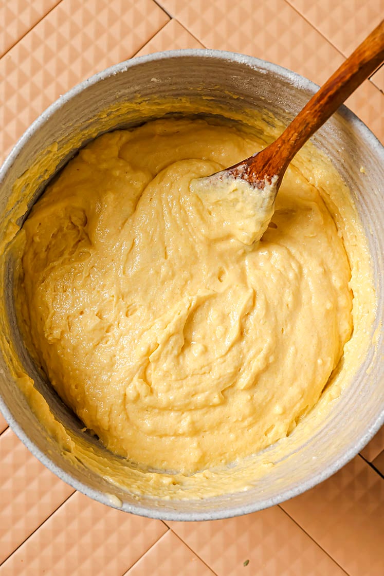 Wet and dry ingredients in a mixing bowl with a wooden spoon.