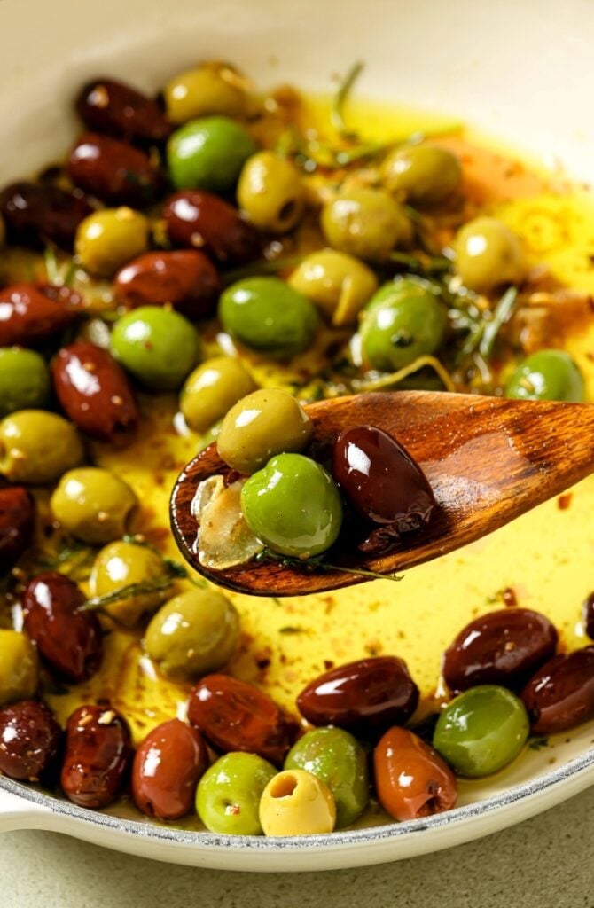 A spoonful of olives in a pan.