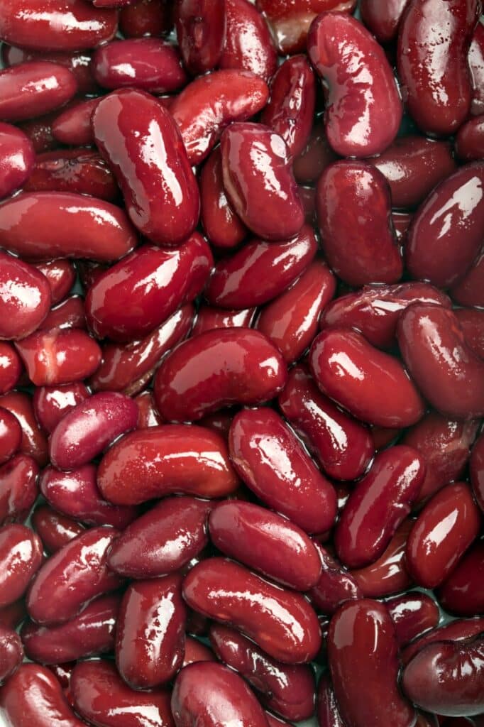 Close-up of numerous shiny red kidney beans displayed, showcasing their smooth texture and rich color.