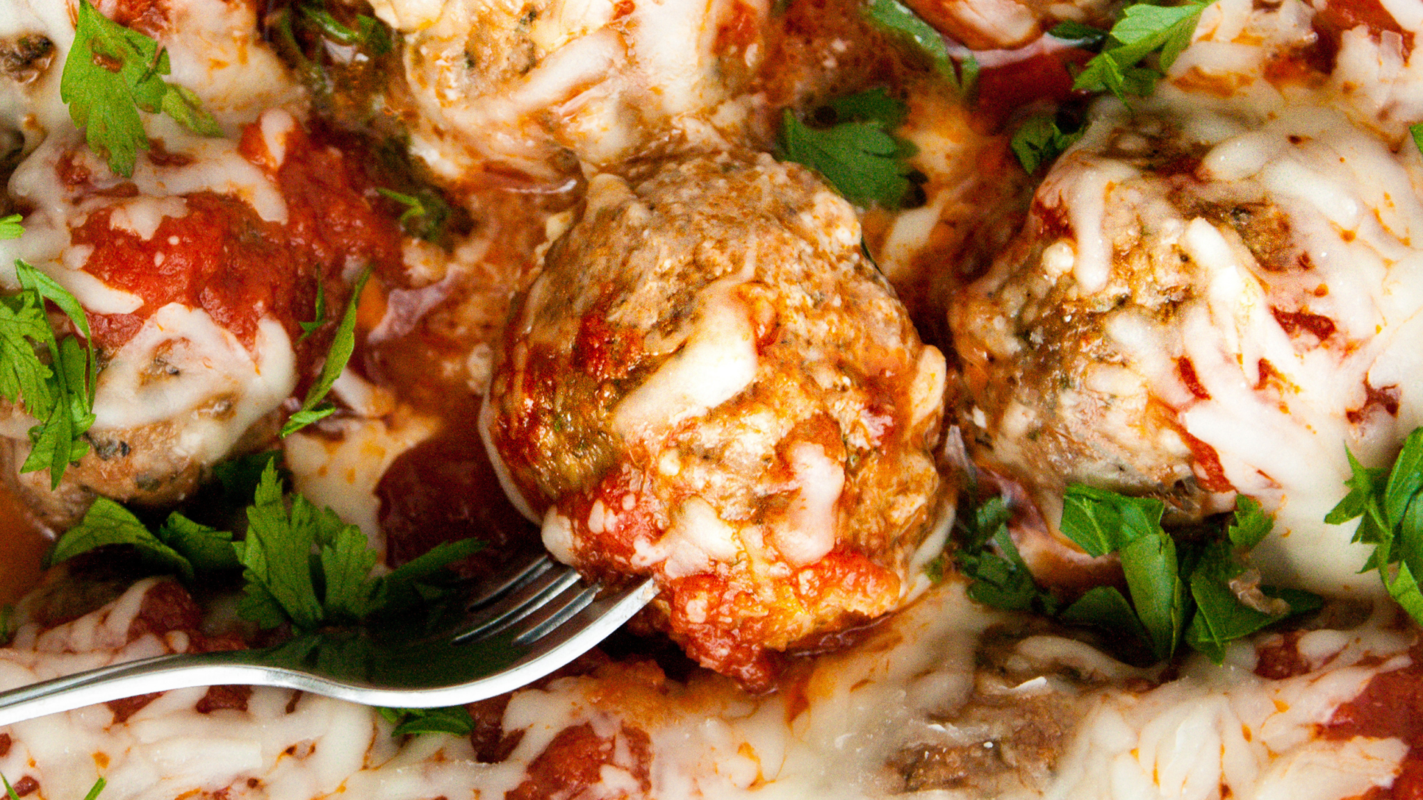 Cheesy Italian meatballs topped with marinara and melted mozzarella, garnished with fresh parsley.