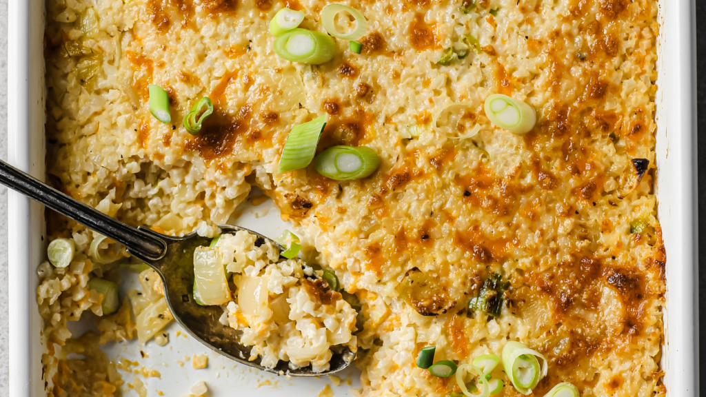 Cauliflower dish being served with silver spoon topped with chopped green onions.