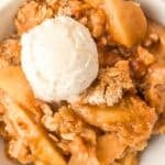 A bowl of apple crisp topped with a scoop of vanilla ice cream. The text "Easy Apple Crisp" appears at the top, and "real balanced" is at the bottom. The dessert looks golden and crumbly with visible apple slices.