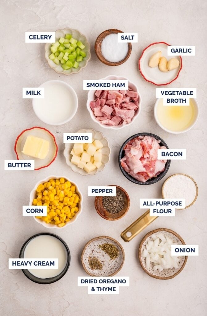 Top-down view of ingredients in small bowls, labeled: celery, salt, garlic, milk, smoked ham, vegetable broth, butter, potato, bacon, corn, pepper, all-purpose flour, heavy cream, dried oregano & thyme, and onion.