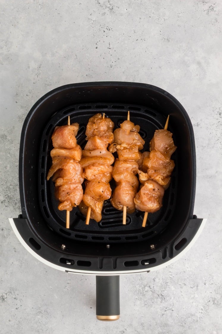 Air fryer chicken skewers arranged in the basket, seasoned and ready to cook for a quick high-protein meal.
