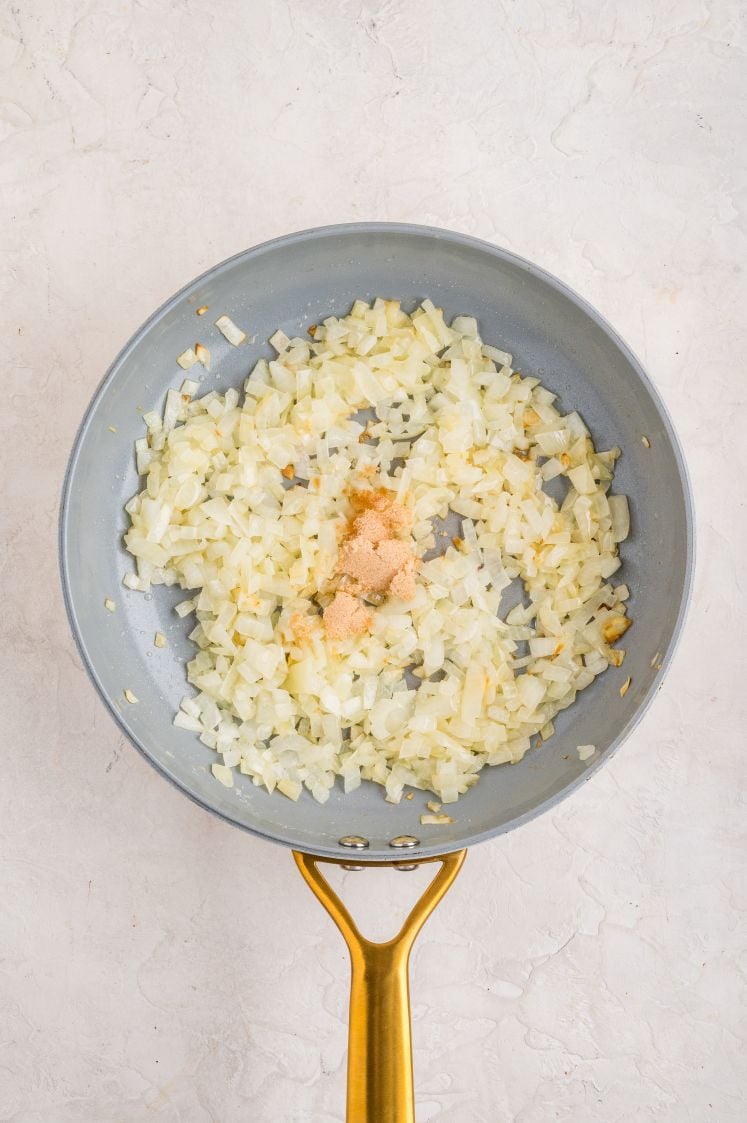 Chopped onions sautéing in a skillet with brown sugar for animal style fries topping.