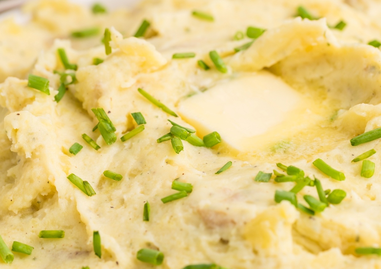 Close-up of mashed potatoes topped with a melting pat of butter and sprinkled with chopped chives.