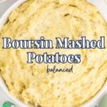 Bowl of creamy mashed potatoes on a table, surrounded by green beans, chopped chives, a Boursin cheese box, and a striped napkin. Text overlay reads "Boursin Mashed Potatoes.