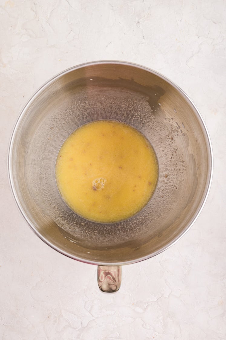A stainless steel mixing bowl filled with a yellow melted butter mixture, showing the first step in preparing the dough for cinnamon pull-apart bread.