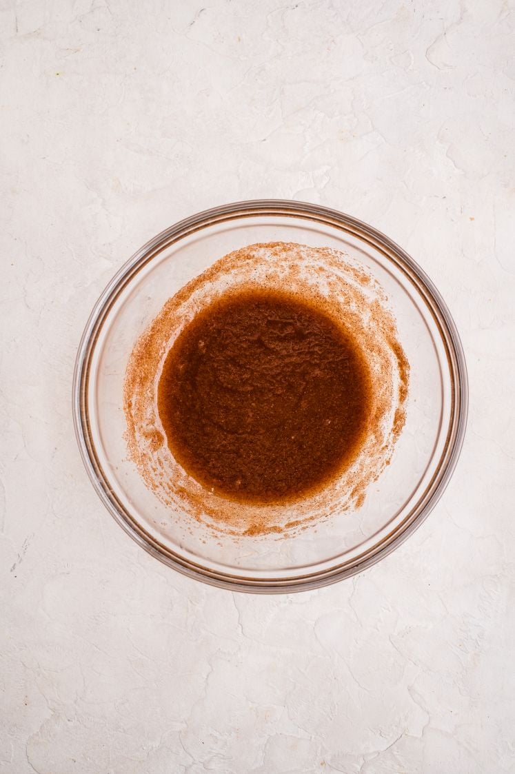 A glass bowl filled with a fully mixed cinnamon-butter filling, showing a smooth, dark brown mixture used for assembling cinnamon pull-apart bread.
