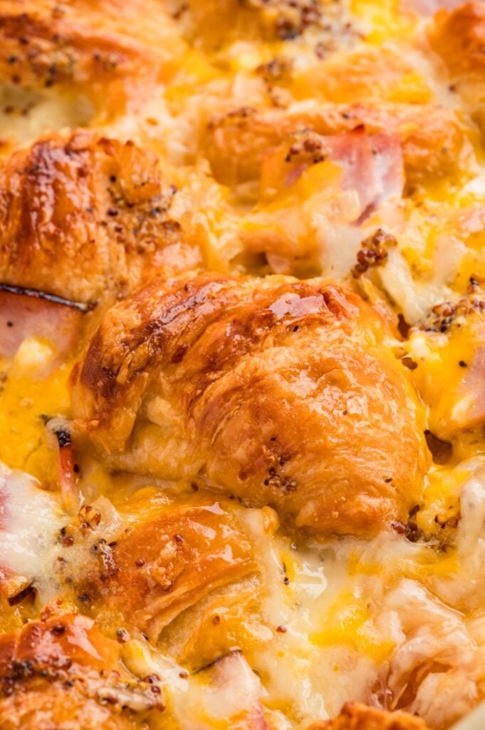 Close-up of a ham and cheese croissant breakfast bake with golden, flaky croissant layers melted together with cheese and diced ham.