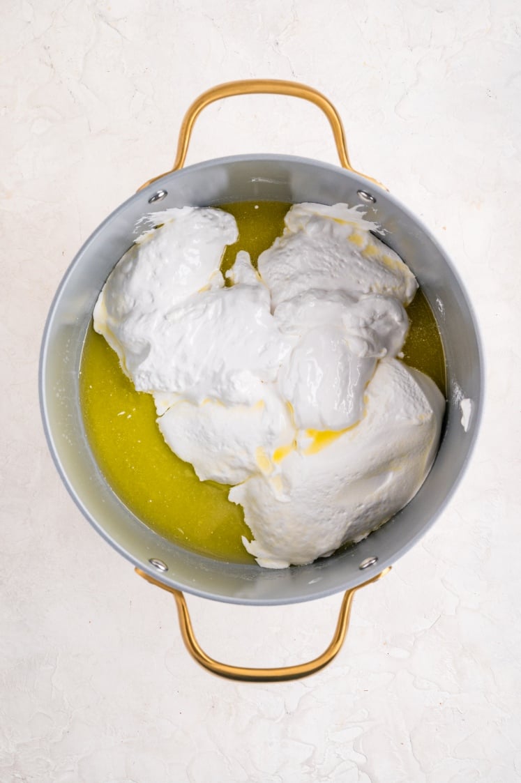 Marshmallow fluff added to melted butter in a pot for Rice Krispie treats.