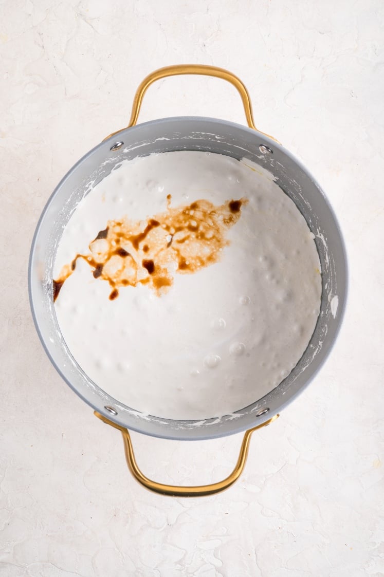 Vanilla extract added to melted marshmallow mixture in a pot for Rice Krispie treats.