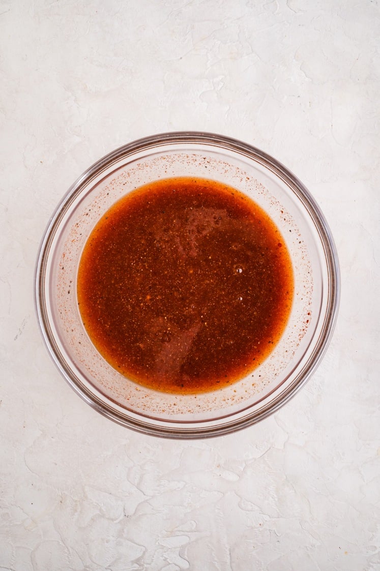 Glass bowl filled with mixed barbecue-style sauce and seasonings.