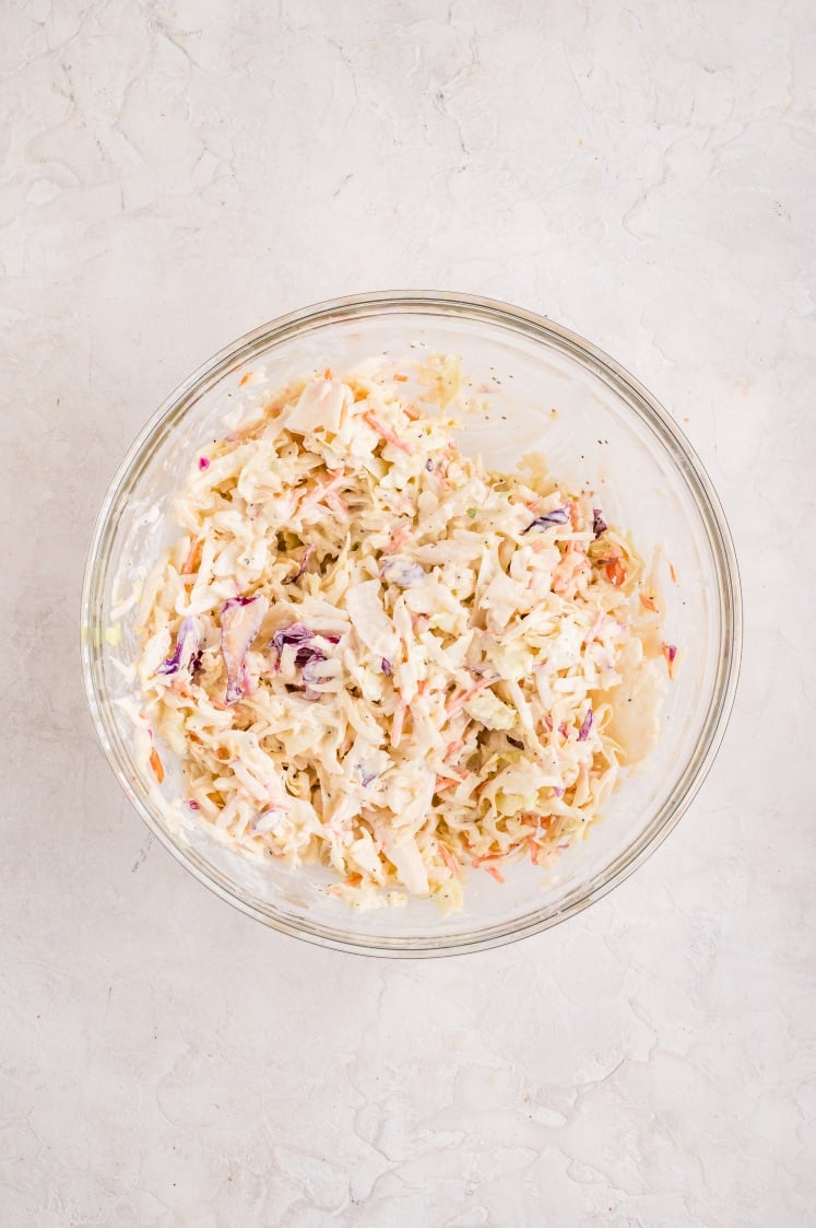 Glass bowl filled with creamy coleslaw made with shredded cabbage and carrots mixed with dressing for Slow Cooker Pulled Chicken.