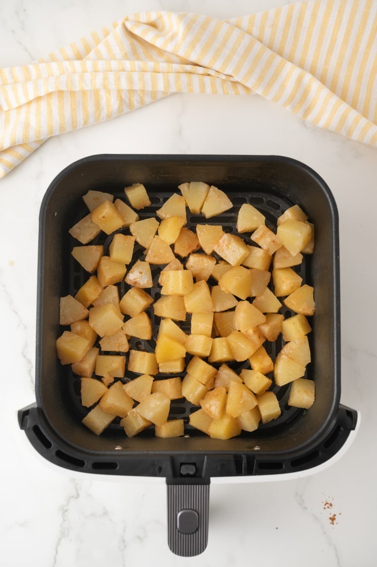 Pineapple chunks in an air fryer basket.
