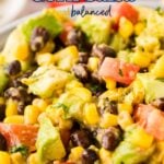 A bowl of black bean and corn salsa with diced avocado, tomato, and herbs, presented up close.