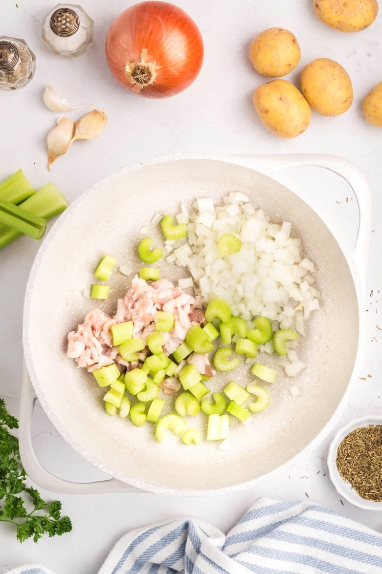 Bacon, onion, and celery cooking in a pot.