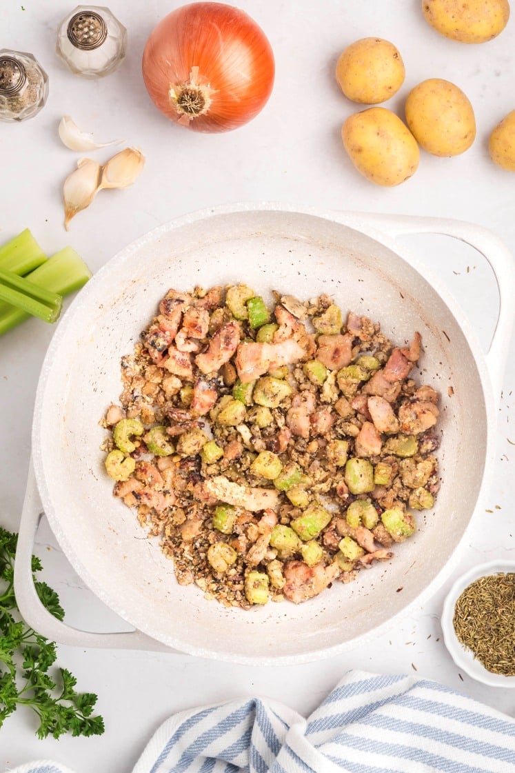 Flour cooked into bacon and celery mixture in a pot.