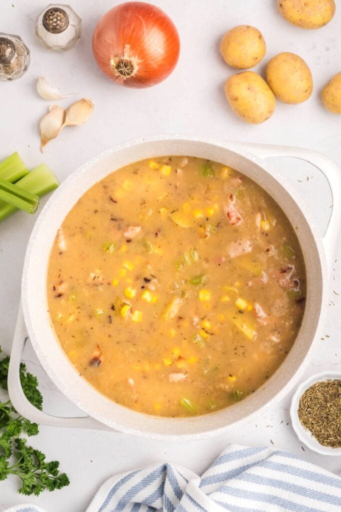 Corn and potato chowder simmering in the pot as the flavors combine.
