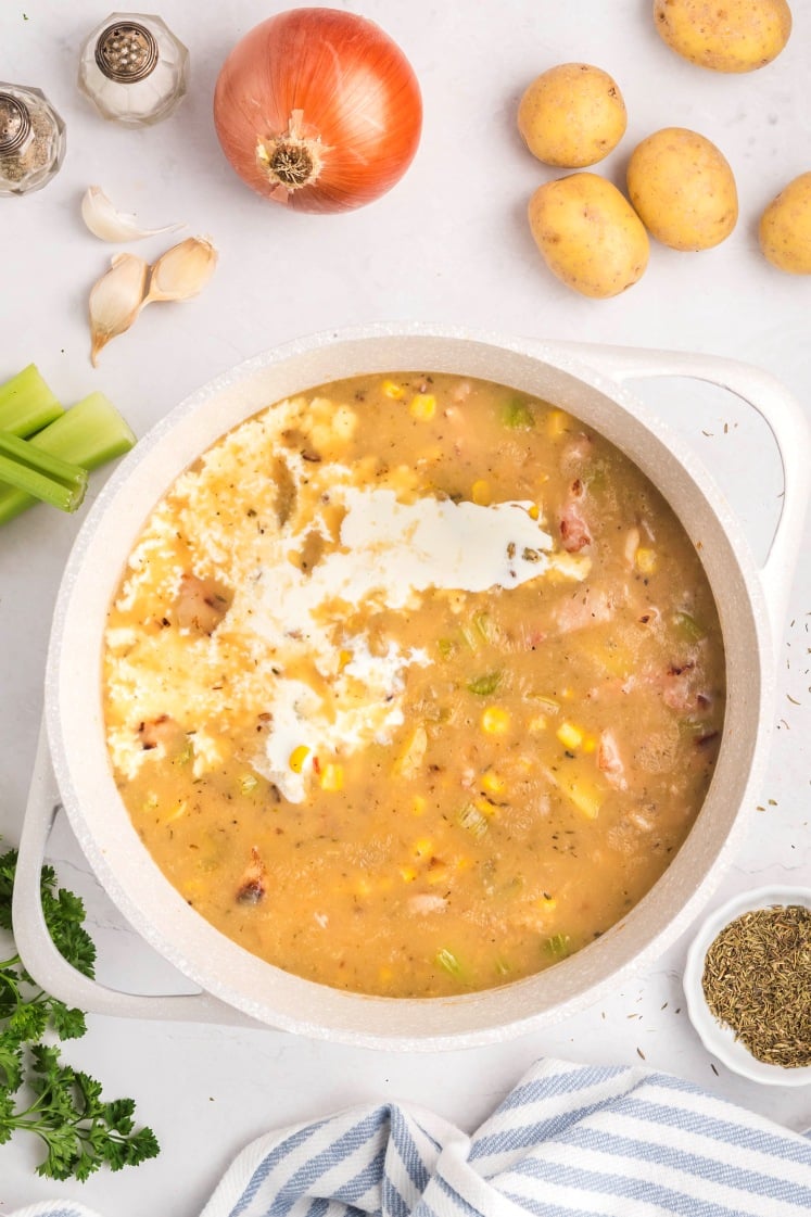 Chowder becoming creamy as heavy cream is added to the pot.