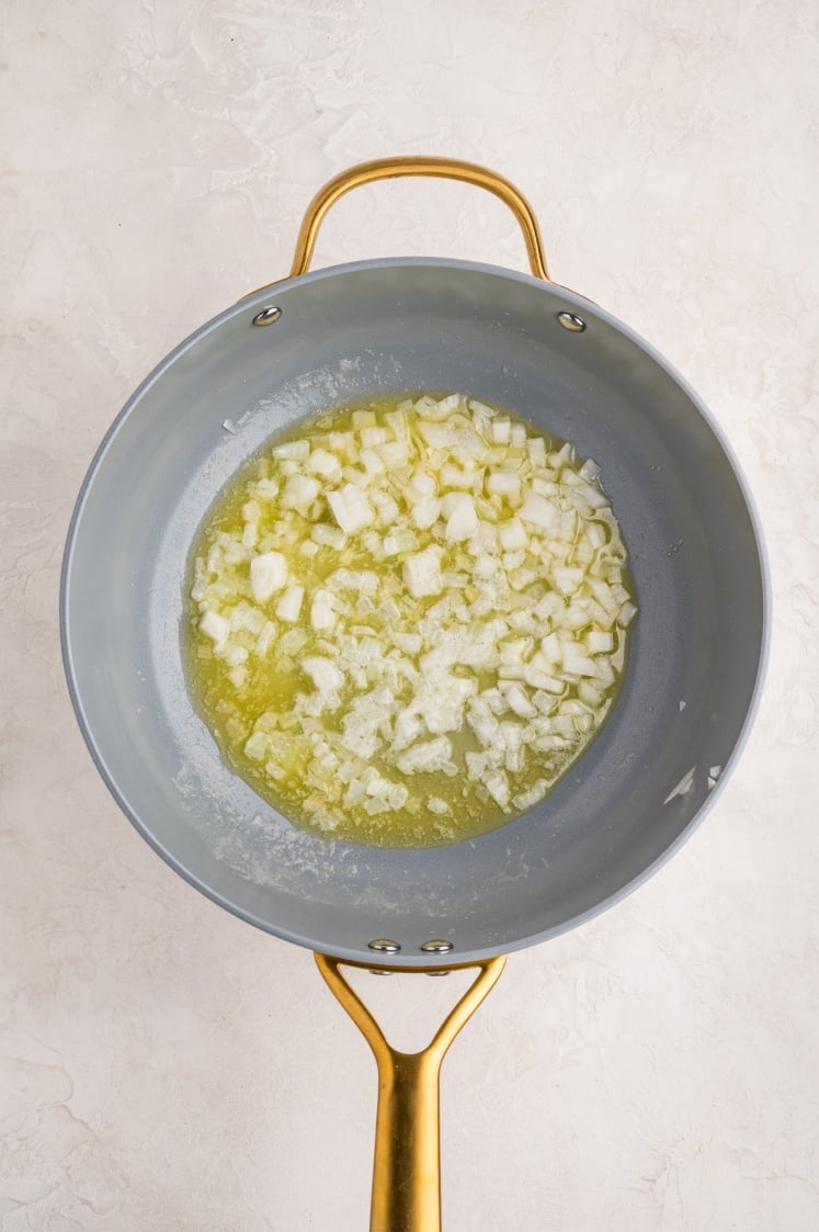 Cooking diced onion in butter in a pan.