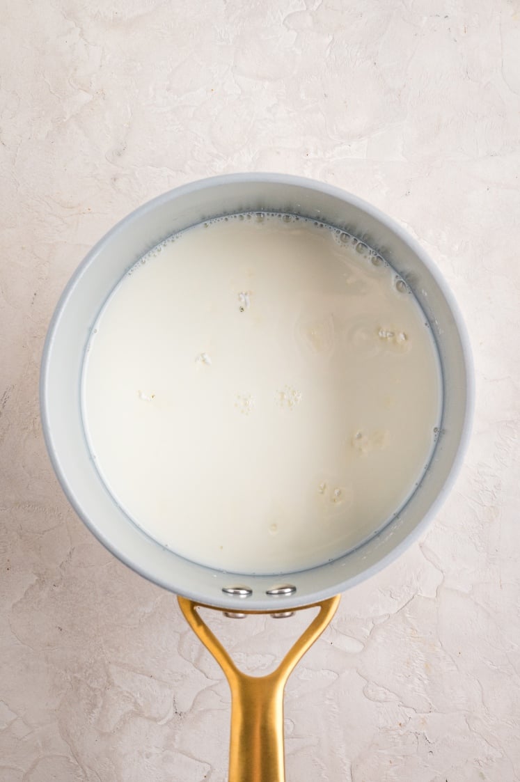 Heating milk in a saucepan to prepare the creamy sauce for French onion chicken casserole.