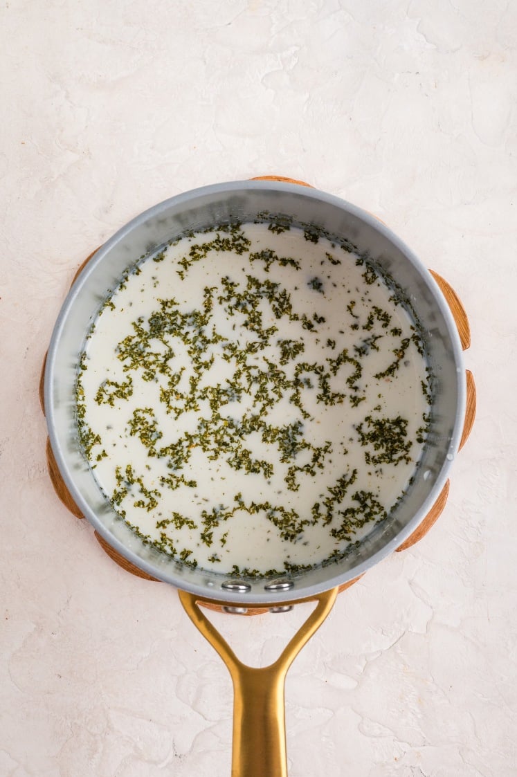 Milk and seasonings simmering in a saucepan to create the creamy base for French onion chicken casserole.