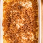 A white baking dish filled with baked French onion chicken casserole, topped with crispy fried onions, shown from above.