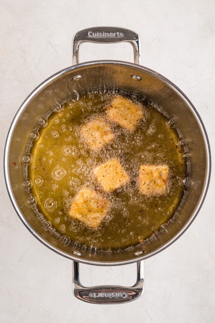 Breaded mac and cheese bites frying in hot oil.
