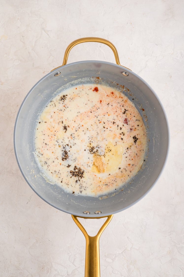 Milk and seasonings added to the roux in a saucepan.