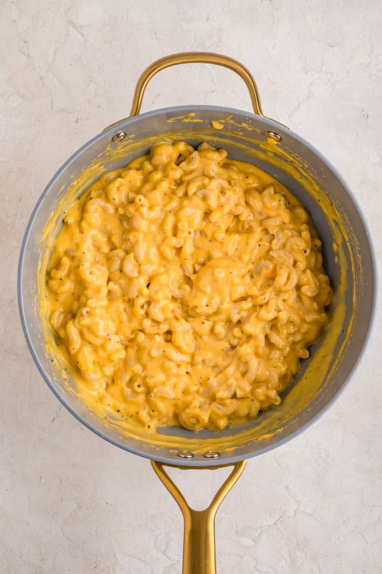 Creamy macaroni and cheese mixed together in a saucepan.