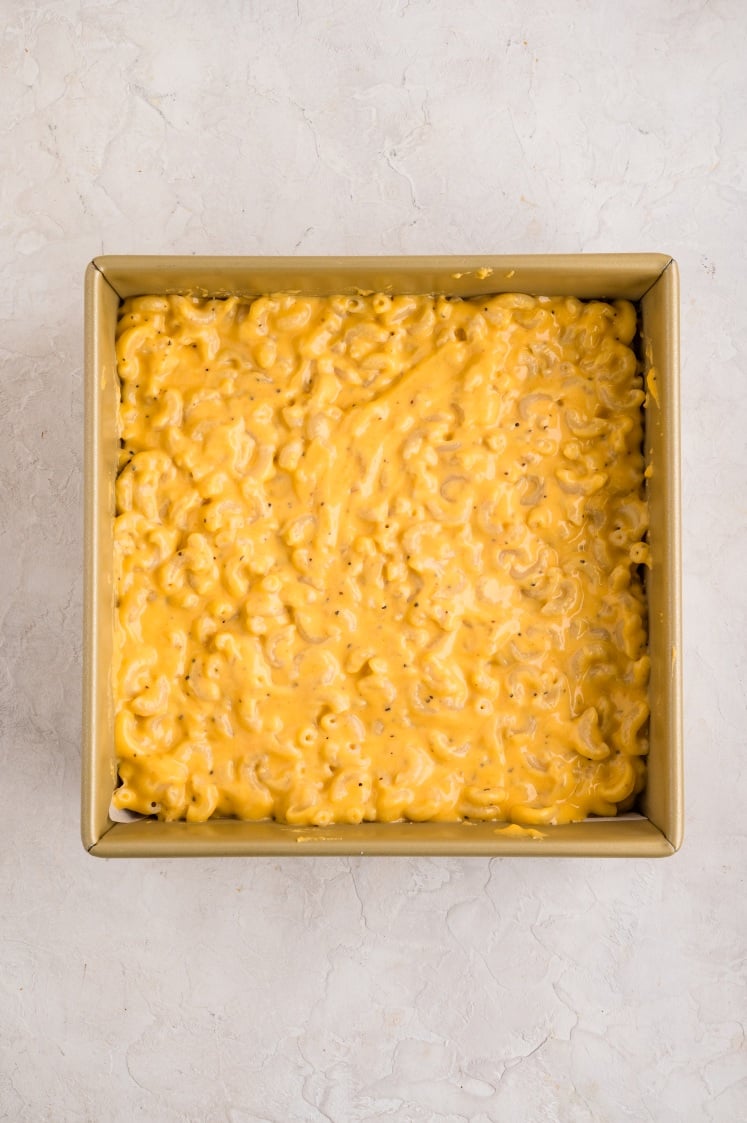Macaroni and cheese spread evenly in a square baking pan.
