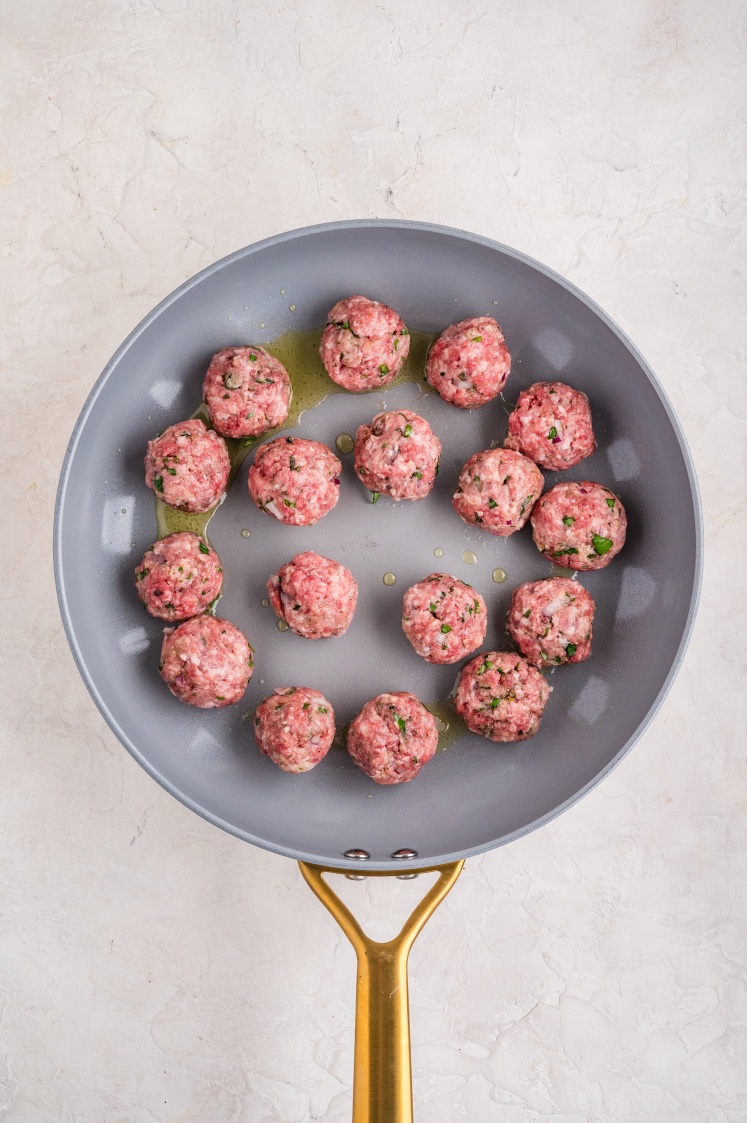 Meatballs placed in a skillet to begin cooking.
