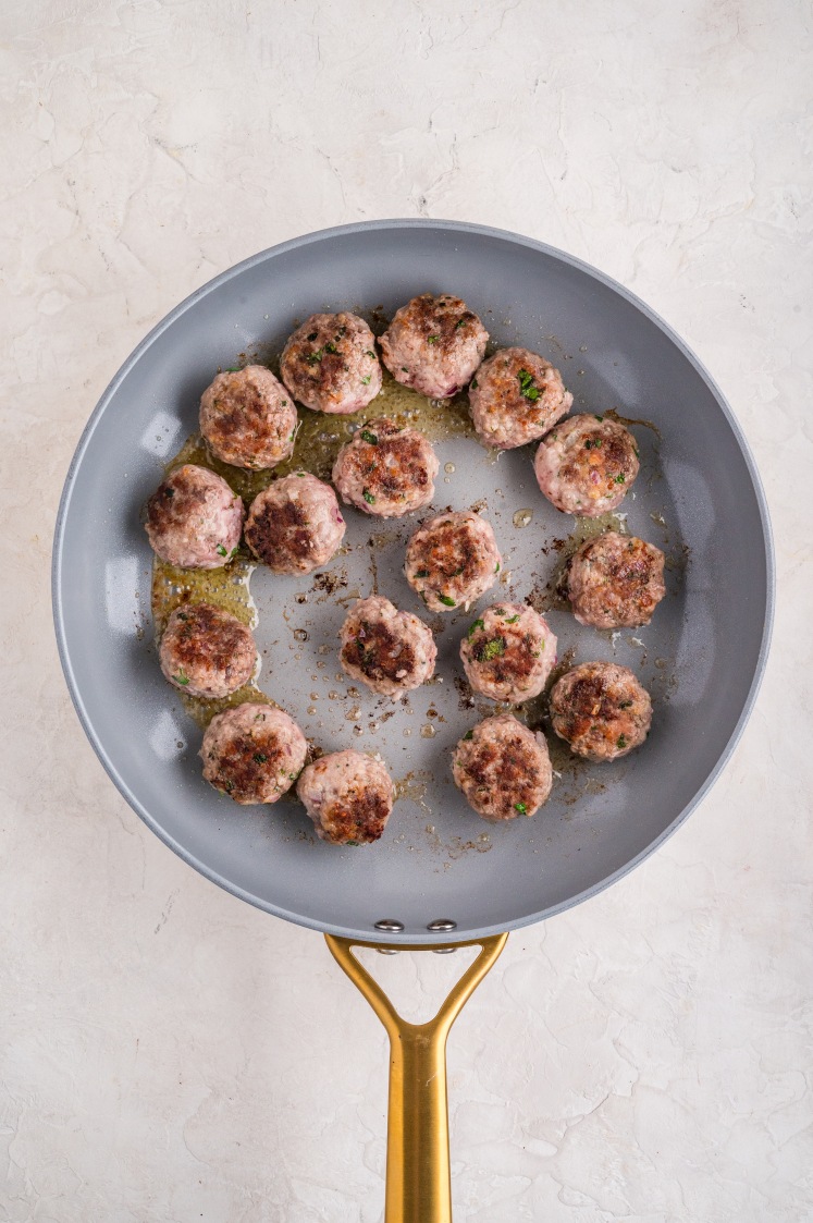 Meatballs browning in a pan.