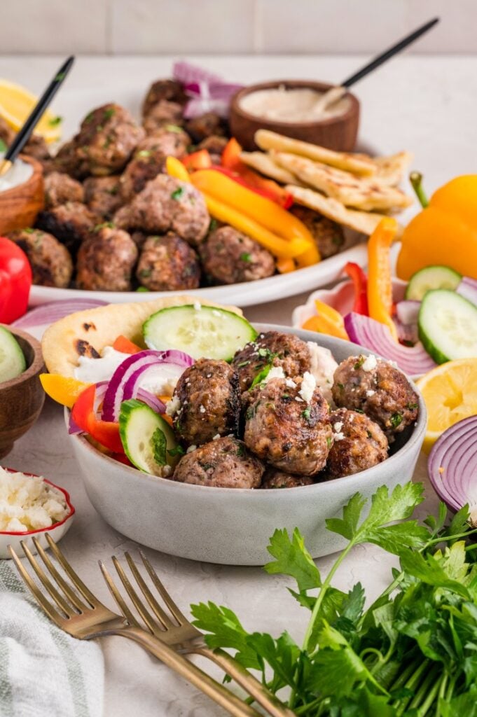 Bowl of Greek meatballs with cucumber, red onion, feta, and pita bread.