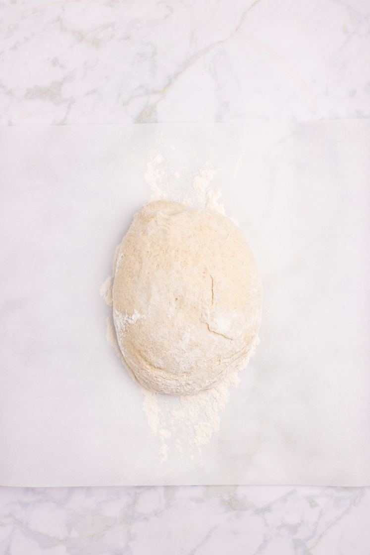 Floured rye dough placed on a sheet of parchment paper, ready to be shaped.